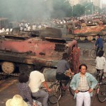 Residents gather next to burnt-out tanks in the aftermath of the crackdown